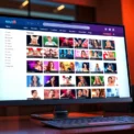 A digital illustration of an adult website interface displayed on a sleek computer screen with colorful thumbnails and navigation elements.